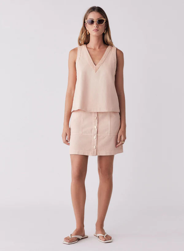 Woman wearing a light pink sleeveless top and skirt on a white background