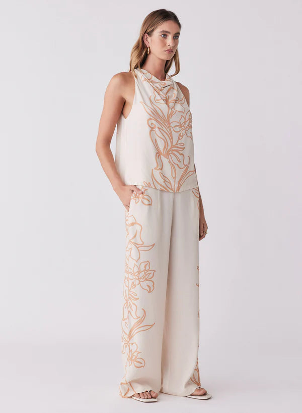Woman wearing a white outfit with gold floral embroidery on a white background