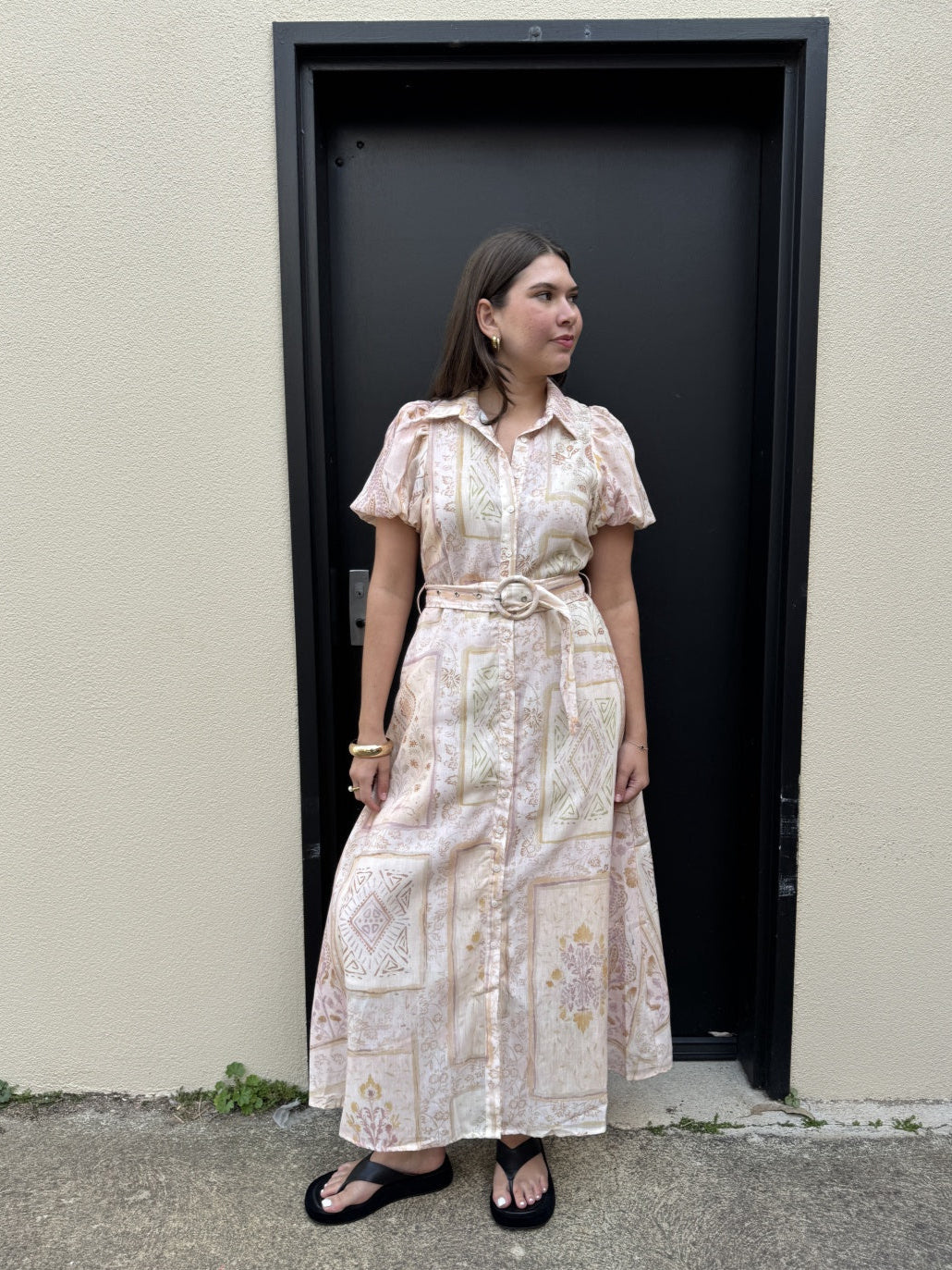 Woman wearing a floral dress standing in front of a black door.