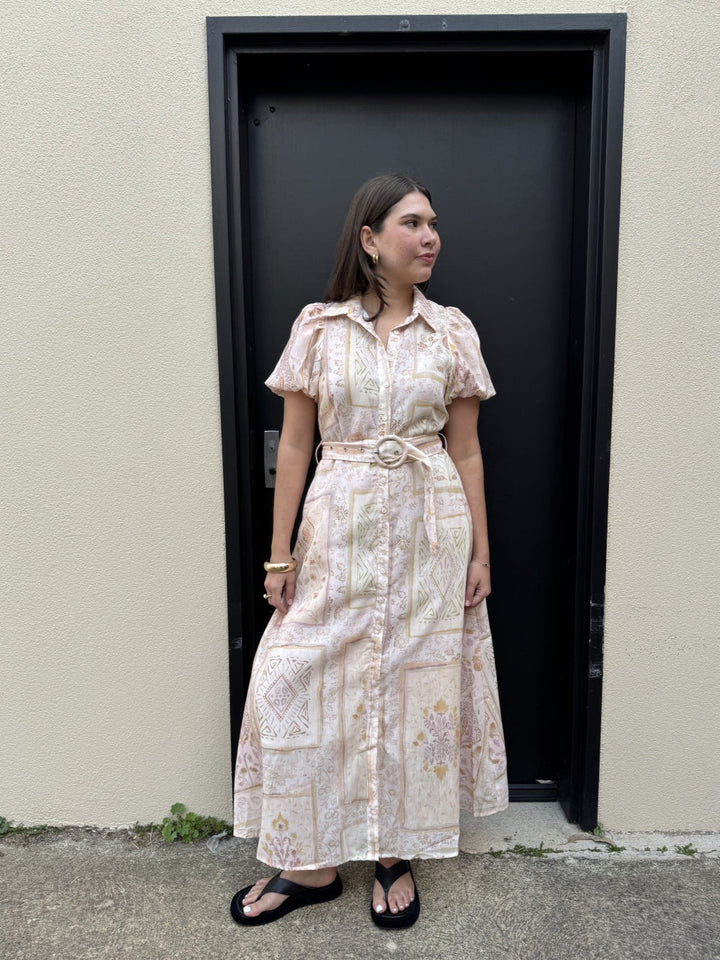 Woman wearing a floral dress standing in front of a black door.