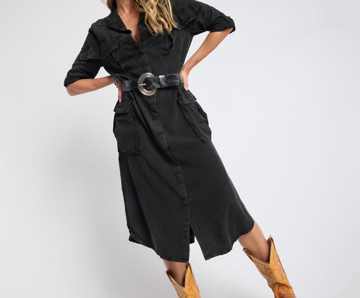 Person wearing a black outfit with a belt and yellow shoes on a white background