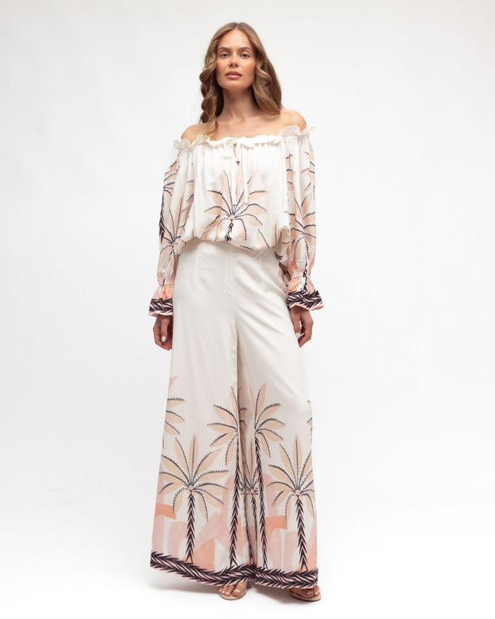 Woman wearing a white outfit with palm tree patterns on a white background