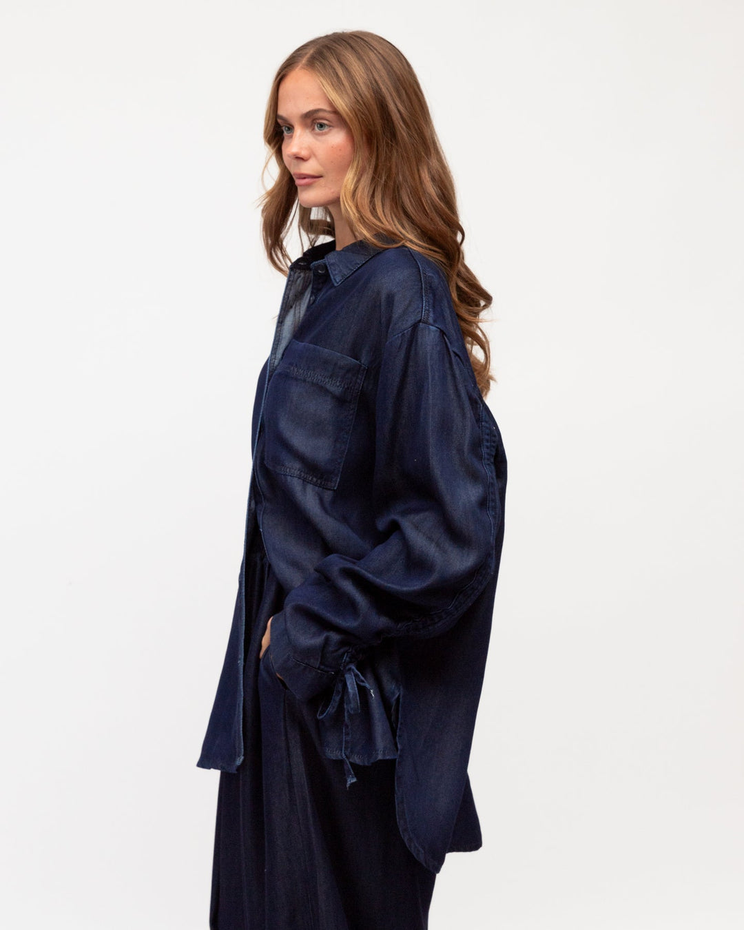 Woman wearing a denim label of love shirt against a white background